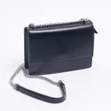 Sobre de mano color negro con textura granulada, solapa frontal y correa de cadena metálica plateada con detalle de cuero en el hombro.