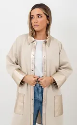 Camisa tipo sobrecamisa de lana en color beige, con detalles en cuero metalizado dorado en cuello, solapa frontal, puños y bolsillos. Presenta cierre frontal con botones a presión.