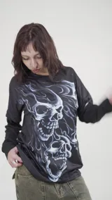 Remera de manga larga con diseño de doble capa, color negro con estampado frontal de calaveras en tonos azulados y efecto de llamas.