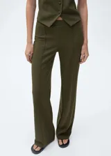 Pantalón de vestir color verde militar, de corte recto y tiro medio. Presenta cintura elástica y costuras verticales decorativas a lo largo de las piernas.