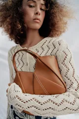 Bolso mini shopper de cuero sintético en color marrón, con diseño estructurado y costuras decorativas contrastantes. Cuenta con doble asa de mano y cierre magnético.