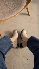 Bota corta de cuero negro con acabado brillante, diseño minimalista, taco cuadrado medio y plataforma delantera. Cuenta con cierre lateral interno para facilitar el calce.