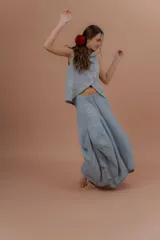 Pollera larga de lino color gris topo, de diseño amplio con volumen, movimiento y bolsillos delanteros. Cuenta con elástico en la cintura y detalles de pinzas y sobretelas en los laterales.
