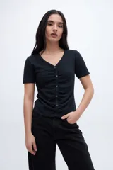 Remera negra con escote en V, cartera de botones, frunces y mangas cortas.