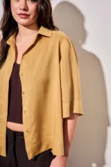 Camisa de lyocell color mostaza, de corte holgado, mangas cortas y cierre frontal con botones.