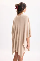 Ruana de punto color beige con hilos de lurex incorporados, diseño abierto y caída fluida.