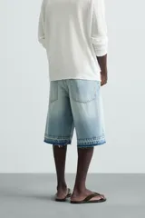 Bermuda de denim de algodón, color negro lavado, de corte ancho (baggy fit) y tiro medio. Presenta cinco bolsillos y bajo con acabado irregular deshilachado.