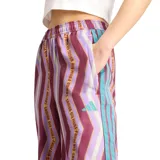 Pantalón ancho de tiro alto, con cintura elástica y estampado de chevron en tonos morados, rosados y blancos. Presenta franjas laterales con texto repetido de la colaboración Adidas x Farm Rio en color turquesa y blanco.