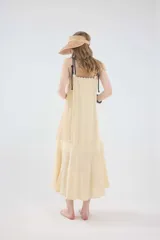 Vestido midi de lino color salmón, de corte amplio y silueta holgada. Presenta diseño con cortes irregulares y detalles de pasamanería en el escote y costuras. Cuenta con breteles dobles tipo cuerda y ruedo asimétrico.