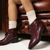 Bota corta de cuero vacuno con acabado metalizado y textura de reptil. Presenta punta fina, cierre lateral interno y taco cuadrado de madera.