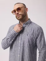 Camisa de manga larga a rayas verticales azules y blancas, con cuello abotonado, bolsillo en el pecho y logo bordado.