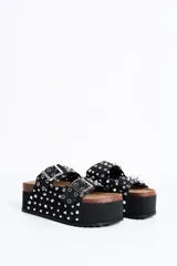 Sandalia plataforma de diseño estilo Birkenstock en color negro, con dos tiras ajustables con hebillas metálicas, decoradas con múltiples tachas y ojales plateados.