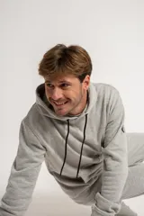 Canguro gris con capucha y cordones negros, bolsillos frontales y puños y cintura acanalados.