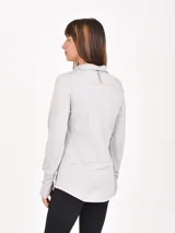 Buzo deportivo gris claro con cuello alto y cierre frontal parcial. Tiene mangas largas con orificios para los pulgares y costuras decorativas que realzan la figura.