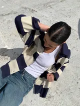 Camisa de manga larga a rayas horizontales azul marino y beige, con cuello camisero, cierre frontal con botones y bolsillo de cuero en el pecho.