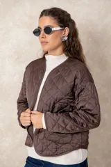 Campera corta de diseño capitoneado con patrón de rombos, color negro. Presenta cuello redondo, cierre frontal abierto, mangas largas y dos bolsillos delanteros con detalle de broche.