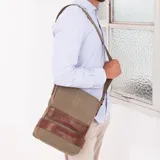 Morral versátil de tela canvas color gris con detalles en cuero sintético marrón. Cuenta con tapa frontal con broches magnéticos, bolsillo tipo guantera bajo la tapa, división interna desmontable con velcro y correa larga regulable.