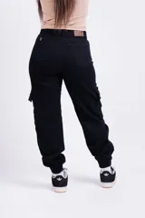 Pantalón mom cargo de jean negro con bolsillos laterales y tobillos ajustados.