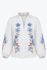 Camisa blanca de manga larga con bordados florales en tono rojo y verde en el frente y las mangas. Presenta cuello mao con escote en V y botones frontales.