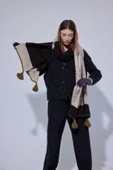 Chal de lana con diseño de patrón paisley y detalles de tejido en punto. Presenta terminaciones con pompones en los extremos.