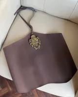 Top halter marrón de ecocuero, con escote recto y tiras ajustables en la espalda. Presenta una aplicación metálica dorada en el centro del pecho con el escudo de Uruguay.