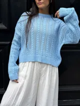 Sweater color crema tejido con diseño en ochos y cuello redondo.