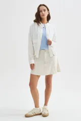 Chaqueta bomber blanca de algodón con cuello mao, bordado sutil, bolsillos frontales con solapa, cierre de botones y cordón ajustable en el ruedo.