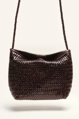 Cartera tipo morral y bandolera de cuero vacuno marrón, completamente trenzada a mano con diseño estructurado y correa larga trenzada.