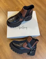 Botas tipo chelsea con suela track gruesa, confeccionadas en cuero genuino. Presentan un diseño bicolor que combina paneles en negro y marrón, con elásticos laterales negros para mayor ajuste y comodidad.