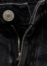 Jeans de corte recto y tiro medio en color negro lavado. Presentan diseño de cinco bolsillos, cierre frontal con cremallera y botón, y un distintivo bajo con vuelta ancha.