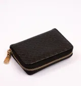 Billetera negra con textura tejida y cierre dorado con dije.