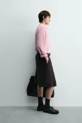 Bermuda negra de corte ancho (wide fit) confeccionada en tejido con mezcla de viscosa. Presenta pliegues en el delantero, bolsillos frontales y bolsillos de vivo en la parte trasera. Cierre frontal con cremallera y gancho metálico oculto.