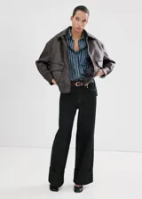 Camisa oversize de algodón estilo denim, de color azul con estampado de rayas, cuello camisero, manga larga con puños abotonados, bolsillo de parche en el pecho y cierre frontal con botones.