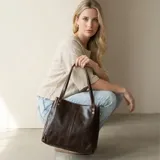 Cartera tipo shopper confeccionada en cuero sintético premium de color marrón oscuro, con doble asa de hombro y diseño estructurado con costuras verticales decorativas.