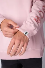 Buzo oversize de cuello redondo en color verde menta, confeccionado en tela rústica. Presenta un pequeño estampado en el pecho y una serie de estampados verticales a lo largo de la manga izquierda.