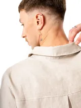 Camisa beige de lino con mangas 3/4, cuello clásico, cierre frontal con botones y bolsillo de parche en el pecho.