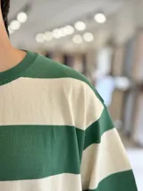 Remera de punto a rayas horizontales en tonos azul marino y beige, de manga corta y corte oversize. Presenta un gran número 15 rojo estampado en la espalda.