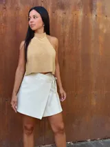 Falda corta tipo wrap de cuero color crudo, con diseño cruzado y ajuste mediante tiritas laterales.