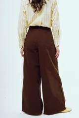 Pantalón marrón de corte ancho y talle alto, con pinzas frontales y bolsillos laterales.