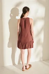 Vestido corto de lino color bordó, sin mangas, con escote redondo, costuras decorativas con flecos y falda estilo globo con volados en el ruedo.
