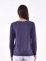 Remera negra de manga larga con cuello redondo y detalle de tachas doradas dispuestas en diagonal sobre el pecho.