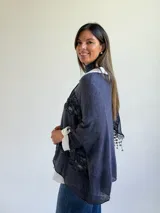 Sweater de punto azul con diseño holgado, que incorpora paneles de encaje floral en el frente y los laterales. Presenta un estilo superpuesto con cuello redondo y mangas largas con puños vueltos.