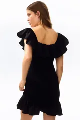 Vestido corto negro en tejido fruncido, de ajuste entallado con hombros descubiertos, escote cuadrado elástico y volado ancho con volumen en escote y bajo.