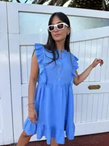 Vestido corto color gris claro, con escote redondo, mangas cortas con volados y falda con volados en el ruedo. Tiene botones en el frente.