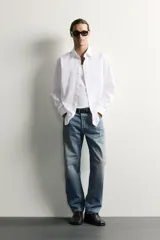 Jeans regular fit confeccionados en denim de algodón celeste con efecto lavado, de cinco bolsillos y cierre frontal con cremallera y botón.