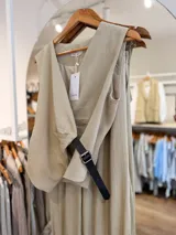 Conjunto de dos piezas para mujer en color beige, compuesto por un chaleco cruzado sin mangas con cinturón lateral y un pantalón de corte amplio.