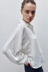 Camisa de viscosa color celeste, de calce amplio y caída fluida, con cuello clásico, cierre frontal de botones y detalles calados en mangas y delantero.