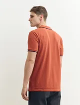 Remera polo azul marino con ribetes blancos en el cuello y en los bordes de las mangas corta, y cierre frontal de botones.