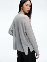 Sweater de tejido fino y semitransparente con hilo brillante. Presenta cuello redondo, hombros caídos y mangas largas amplias con un ajuste relajado y caída fluida.