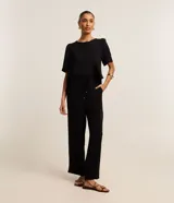 Blusa negra de mangas cortas abullonadas, confeccionada en tejido airflow con textura arrugada y abertura en forma de gota en la espalda.